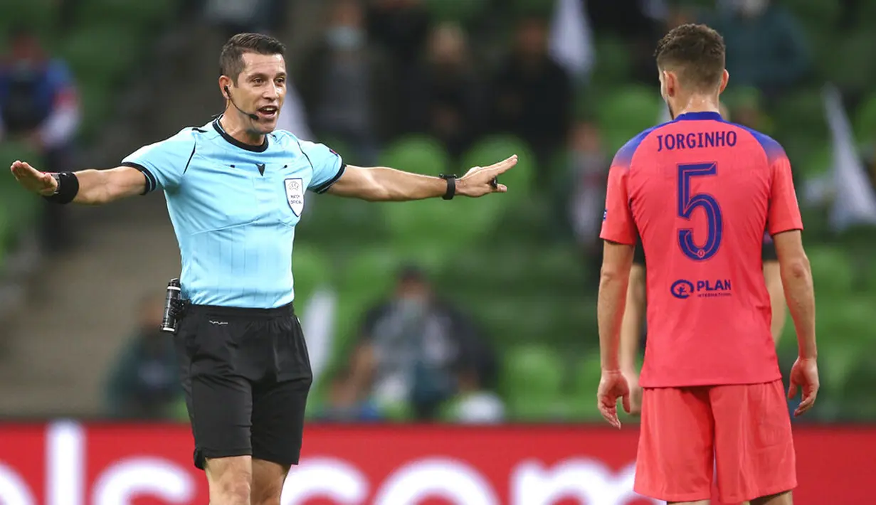 Wasit Ali Palabiyik memberi isyarat di depan pemain Chelsea Jorginho saat menghadapi Krasnodar pada pertandingan Grup E Liga Champions di Krasnodar, Rusia, Rabu (28/10/2020). Chelsea membungkam Krasnodar dengan skor 4-0. (AP Photo)