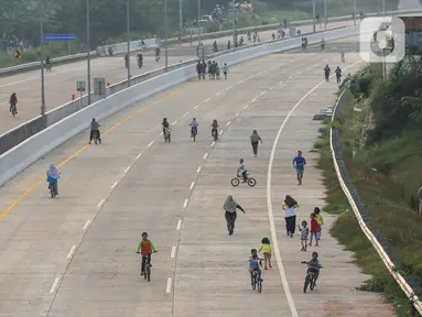 Warga berolahraga sepeda dan berlari pada waktu sore di kawasan pembangunan Tol Serpong Kunciran, Ciputat, Tangerang Selatan, Kamis (25/6/2020). Pembangunan tol yang belum rampung dimanfaatkan sejumlah warga beraktivitas selama pandemi Covid-19. (Liputan6.com/Fery Pradolo)