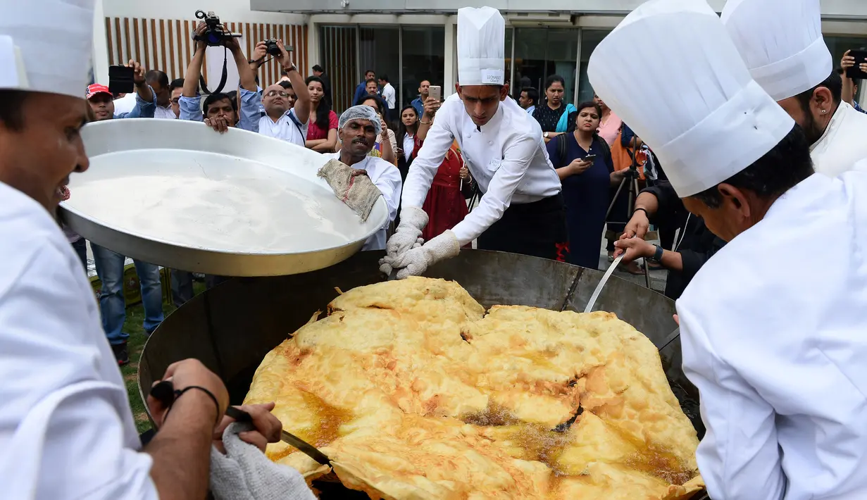 Roti goreng Bhatura dengan diameter 147 cm siap diangkat, India, New Delhi, Kamis (6/4). Penyelenggara berharap Bhatura buatan mereka bisa memecahkan rekor Bhatura  terbesar di India. (AFP PHOTO / SAJJAD HUSSAIN)