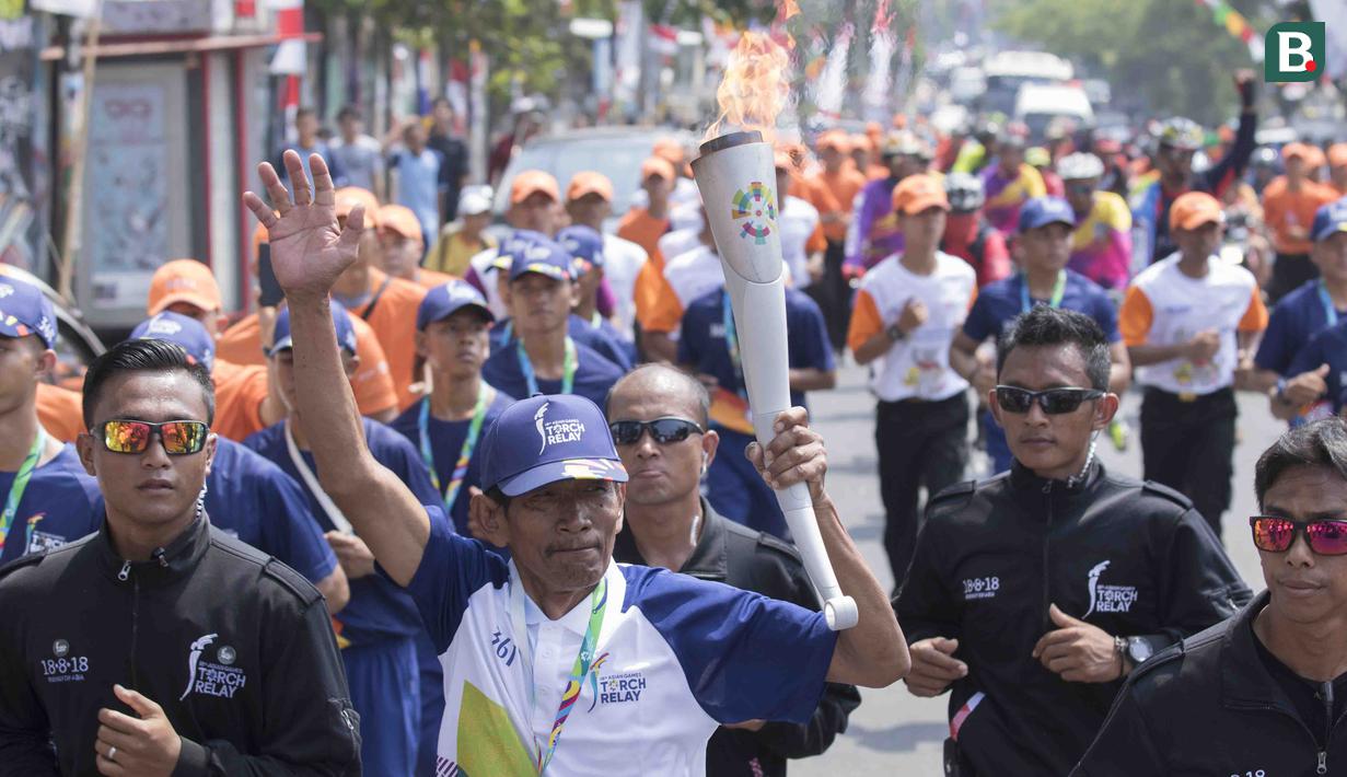 Pebalap sepeda legendaris Indonesia, Sutiyono, berlari saat mengikuti pawai obor Asian Games XVIII di Lampung, Rabu (8/8/2018). Sebanyak 53 kota di Indonesia akan dilalui oleh obor Asian Games. (Bola.com/Reza Bachtiar)