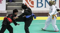 Pesilat Nirmalasari Oktaviani berusaha menahan tendangan pesilat Laos Olathai Sounthavong di semifinal 50-55 kg putri cabang Pencak Silat 18th Asian Games Invitation Tournament, Jakarta, Senin (12/2). Indonesia menang 5-0. (Liputan6.com/Faizal Fanani)