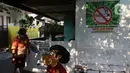 Warga melintas dekat stiker kawasan bebas asap rokok di lingkungan RW 06 Kelurahan Kayu Manis, Matraman, Jakarta, Jumat (8/10/2021). Beberapa titik pada kawasan tersebut juga terdapat mural-mural tentang pemberitahuan serta peringatan untuk tidak dan berhenti merokok (Liputan6.com/Herman Zakharia)