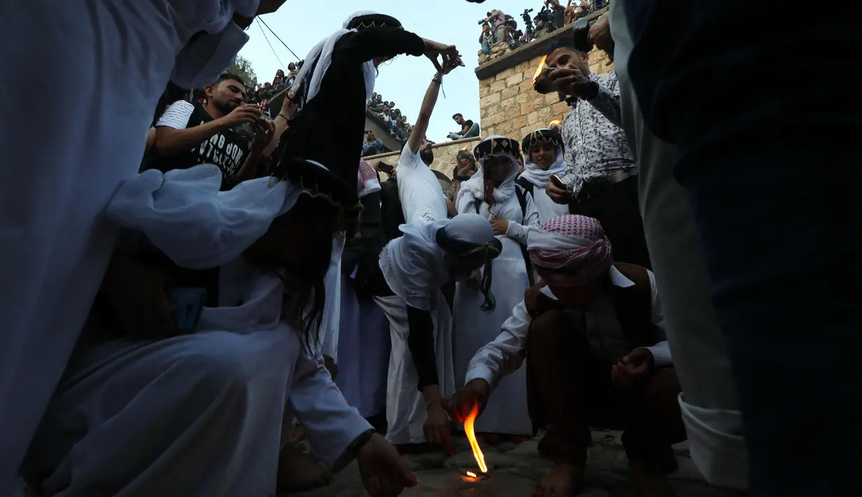Kelompok Yazidi Irak menyalakan obor parafin di luar kuil Lalish saat perayaan Tahun Baru Yazidi di lembah dekat Dohuk, Irak (17/4). Agama Yazidi sekilas seperti perpaduan antara Islam, Kristen dan Zoroaster. (AFP/Safin Hamed)