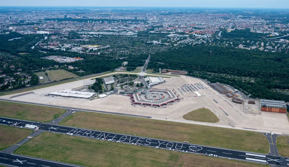 Pemandangan udara dari helikopter menunjukkan meja-meja yang ditata dalam bentuk pesan bertuliskan 'Berlin Loves You' (Berlin Mencintaimu) saat 3.000 warga menghadiri acara Berlin Freedom Dinner di landasan pacu bekas bandara Tegel di Berlin pada 7 Agustus 2021. (Christophe Gateau / DPA / AFP)