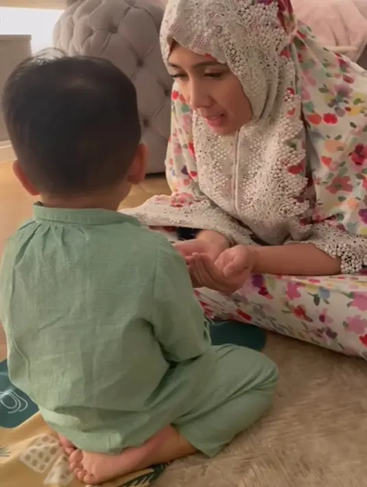 Interaksi gemas antara Nagita Slavina dan Rafathar setelah salat. Nagita Slavina tampil mengenakan mukena bercorak floral yang semarak dengan warna dasar putih. [Foto: Instagram/raffinagita1717]