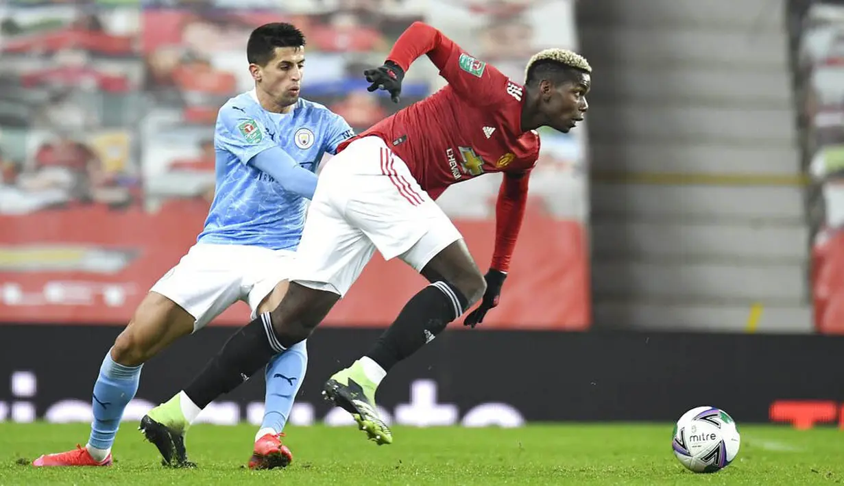 Bek Manchester City, Joao Cancelo, berebut bola dengan pemain Manchester United, Paul Pogba, pada laga Piala Liga Inggris di Stadion Old Trafford, Rabu (6/1/2021). City menang dengan skor 2-0. (Peter Powell/Pool via AP)