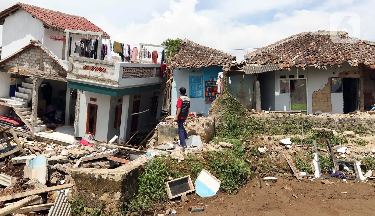 Warga melihat sejumlah rumah yang rusak akibat gempa di Desa Sarampad, Kabupaten Cianjur, Jawa Barat, Selasa (22/11/2022). Gempa dengan magnitudo 5,6 mengakibatkan sejumlah rumah dan jalan di Desa Sarampad rusak parah. (Liputan6.com/Herman Zakharia)
