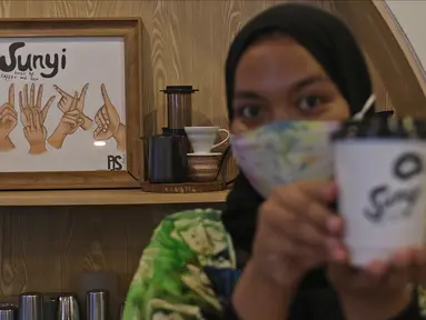 Barista menunjukkan kopi buatannya di Sunyi House of Coffee and Hope, Jakarta, Jumat (15/1/2021). Rumah kopi ini mempekerjakan difabel untuk melayani pengunjung dan mengajari bahasa isyarat alfabet. (Liputan6.com/Herman Zakharia)