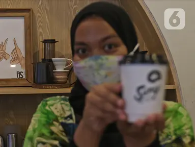Barista menunjukkan kopi buatannya di Sunyi House of Coffee and Hope, Jakarta, Jumat (15/1/2021). Rumah kopi ini mempekerjakan difabel untuk melayani pengunjung dan mengajari bahasa isyarat alfabet. (Liputan6.com/Herman Zakharia)