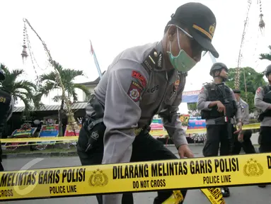 Petugas memasang garis polisi di lokasi bom bunuh diri di Mapolresta Solo, Jawa Tengah, Selasa (5/7). Garis polisi tersebut dipasang mulai dari sisi barat jalan Adi Sucipto menuju sisi timur Jalan KS Tubun. (Liputan6.com/Boy Harjanto)