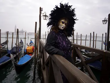 Peserta mengenakan kostum dan topeng berpose untuk difoto saat berpartisipasi dalam Karnaval Venesia di Italia (27/1). Karnaval Venesia adalah festival yang rutin diadakan setiap tahunnya di kota Venesia, Italia. (AFP Photo/Filippo Monteforte)