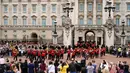 Orang-orang menyaksikan prosesi pergantian penjaga di Istana Buckingham, London, Senin (23/8/2021). Pergantian pasukan jaga yang dilengkapi dengan alat musik lengkap ala marching band tersebut berlangsung untuk pertama kalinya sejak dimulainya pandemi corona Covid-19. (AP Photo/Alberto Pezzali)