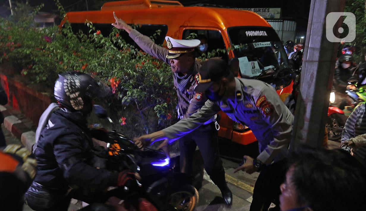 Petugas kepolisian saat menghalau pemudik yang akan menerobos trotoar di Jalan Kedungwaringin, Kabupaten Bekasi, Jawa Barat, Minggu (9/5/2021). Pemudik memblokir jalan saat penyekatan di posko penyekatan mudik di Kedungwaringin. (Liputan6.com/Herman Zakharia)