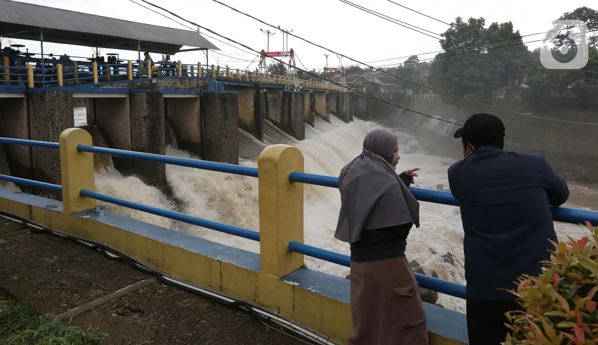 Warga melihat debit air di Bendung Katulampa, Bogor, Jawa Barat, Jumat (19/2/2021). Meski sempat mengalami kenaikan debit air pada Jumat (19/2) pagi, namum sekitar pukul 15.00 WIB, debit air di Bendung Katulampa berada di zona hijau dengan ketinggian sekitar 50 cm. (Liputan6.com/Helmi Fithriansyah)