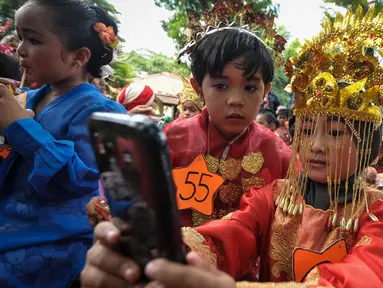 Murid TK Sekolah Alternatif untuk Anak Jalanan (SAAJA) ber-selfie dengan mengenakan pakaian adat di kawasan Kuningan, Jakarta, Selasa (21/4/2015). Kegiatan tersebut dalam rangka Hari Kartini yang diperingati setiap 21 April. (Liputan6.com/Faizal Fanani)