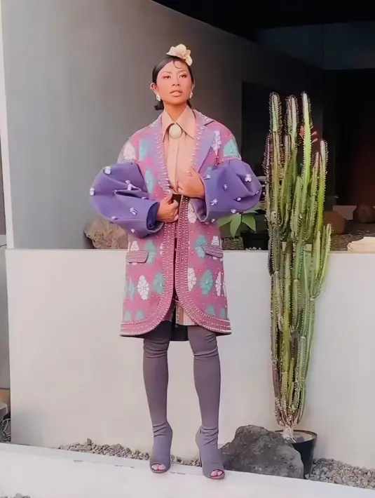 Dira Sugandi membawakan lagu “Mahadaya Cinta”  mengenakan long outer bergaya etnik rancangan Priyoko Oktaviano. Outer tersebut dipadukan dengan kemeja pink dan sepatu boots ungu. [Instagram/dirasugandi]