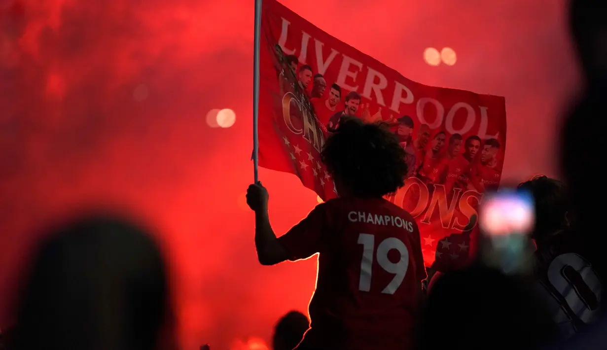 Seorang pendukung Liverpool merayakan gelar juara Liga Premier di luar Stadion Anfield, Kamis (25/6/2020). Trofi juara Liga Primer musim 2019-2020 Trofi juara Liga Primer musim 2019-2020 tersebut dimenangkan Liverpool setelah Manchester City takluk 1-2 dari Chelsea. (AP/Jon Super)