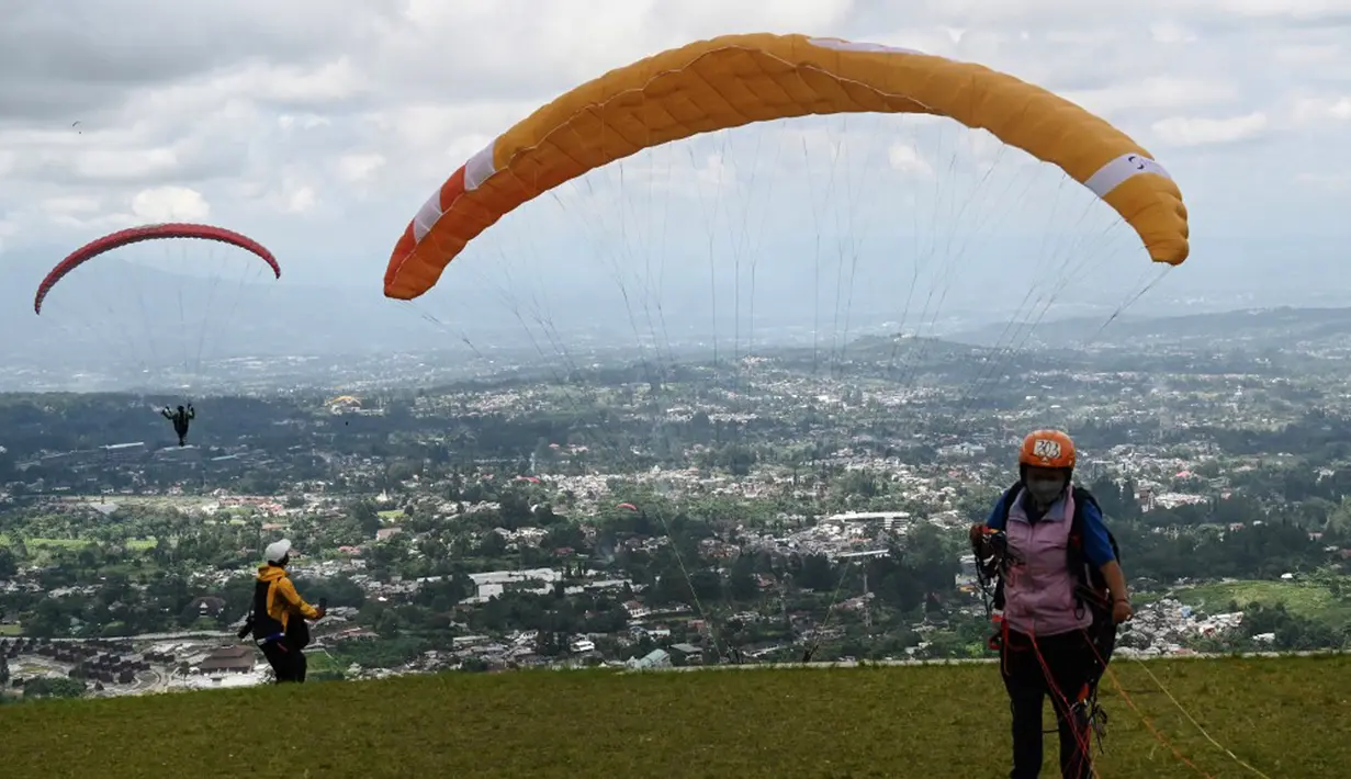 Seorang paraglider bersiap untuk lepas landas dari lereng bukit di Puncak, Bogor, Jawa Barat, Kamis (2/12/2021). Destinasi wisata alam Bukit Paralayang Puncak Bogor sangat cocok untuk dikunjungi pada liburan akhir pekan bersama keluarga, sahabat maupun pasangan tercinta. (Goh Chai Hin/AFP)