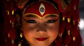 Seorang gadis muda berpakaian seperti dewi Kumari bereaksi terhadap kamera saat menunggu Kumari Puja, sebuah ritual pemujaan di Hanuman Dhoka, Basantapur Durbar Square, Kathmandu, Nepal, Rabu, 27 September 2023. (AP Photo/Niranjan Shrestha)