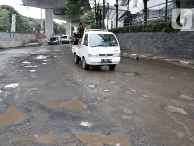 Kendaraan melintas dekat jalan berlubang di kawasan Kelapa Gading, Jakarta, Minggu (1/3/2020). Kepala Dinas Bina Marga DKI Jakarta Hari Nugroho mengatakan banjir pada Februari 2020 merusak 495 jalan Ibu Kota dengan 3.290 titik lubang yang tersebar di lima wilayah. (merdeka.com/Iqbal Nugroho)