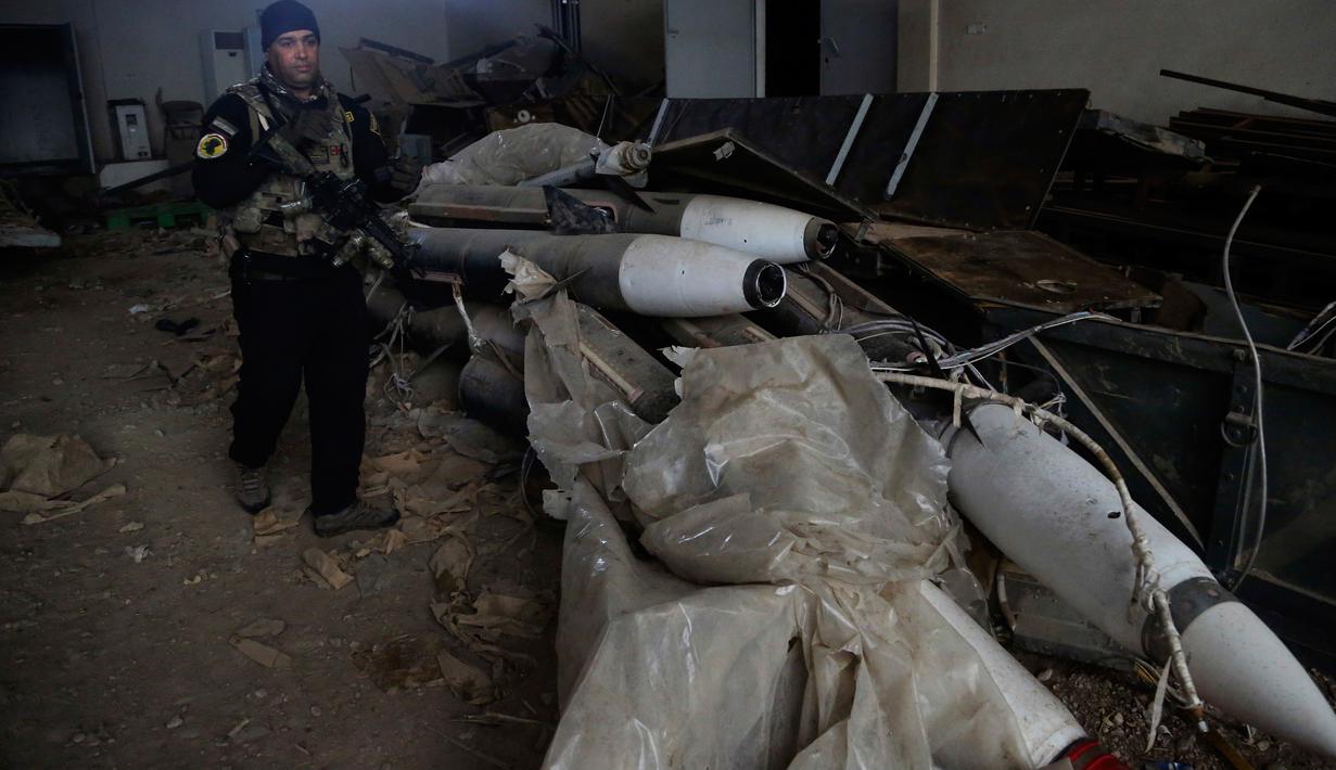 Pasukan khusus Irak berjalan dekat rudal yang ditemukan di sebuah gudang senjata milik ISIS di sisi timur Mosul, Sabtu (28/1). Senjata-senjata yang ditemukan di antara puluhan roket yang tersembunyi di unit penyimpanan di kota. (AP Photo/Khalid Mohammed)
