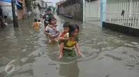 Sejumlah anak menggendong adiknya melewati banjir di Rawa Buaya, Jakarta, Minggu (28/2/2016). Banjir akibat luapan Kali Mookervart ini menyebabkan ratusan rumah warga tergenang air rata-rata satu meter. (Liputan6.com/Gempur M Surya)