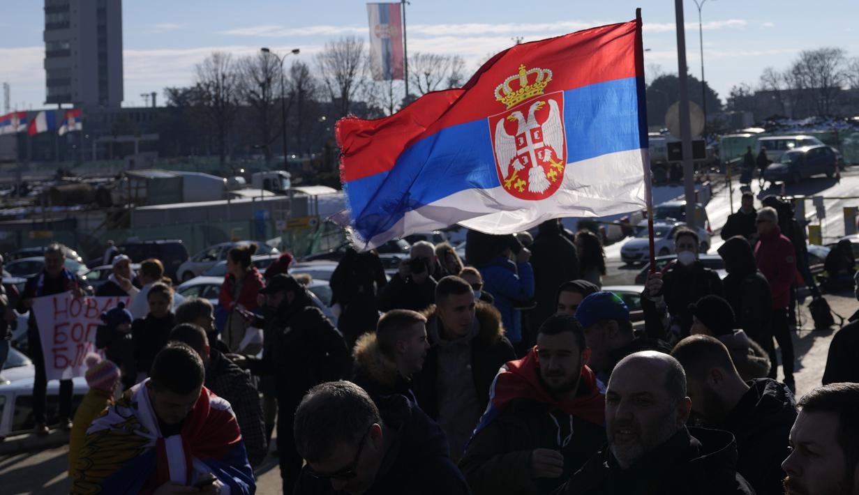 Penggemar mengibarkan bendera nasional Serbia saat Novak Djokovic tiba di bandara Nikola Tesla di Beograd, Senin (17/1/2022). Petenis nomor satu dunia Novak Djokovic tiba di ibu kota Serbia setelah dideportasi dari Australia pada hari Minggu terkait status vaksinasinya (AP Photo/Darko Vojinovic)