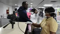 Anggota staf Layanan Kesehatan Port berdiri di sebelah pemindai termal saat penumpang tiba di Bandara Internasional Murtala Mohammed di Lagos, Nigeria, pada 27 Januari 2019. (AFP)