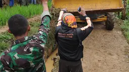 Warga memandu alat berat melalui jalan kecil menuju lokasi longsor di Dusun Cimapag, Sirnaresmi, Cisolok, Sukabumi, Jawa Barat, Selasa (1/1). Korban meninggal longsor Sukabumi bertambah menjadi lima orang. (Merdeka.com/Arie Basuki)