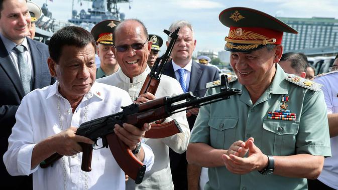 Presiden Filipina Rodrigo Duterte bersama Menhan Rusia, Sergei Shoigu (kanan) memegang senapan serbu AK-47 sumbangan dari Rusia di atas kapal perusak Rusia Admiral Panteleyev di pelabuhan Metro Manila, Filipina (25/10). (AFP Photo/Robinson Ninal)