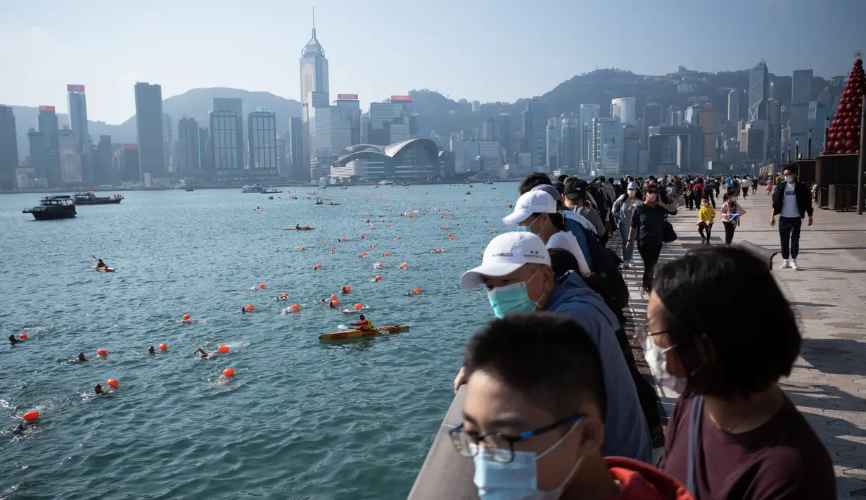 Penonton menyaksikan perlombaan renang melintasi Pelabuhan Victoria Hong Kong dari daerah Tsim Sha Tsui, Minggu (12/12/2021). Lomba renang tahunan itu diadakan untuk pertama kalinya dalam tiga tahun, setelah dibatalkan karena demonstrasi besar-besaran dan kemudian pandemi COVID-19. (Bertha WANG/AFP)