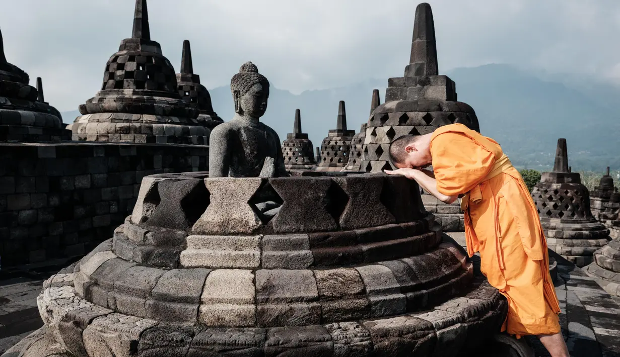 Seorang biksu Buddha berdoa di depan patung di salah satu stupa Candi Borobudur di Magelang, Jawa Tengah, pada 10 Mei 2025. (YASUYOSHI CHIBA/AFP)