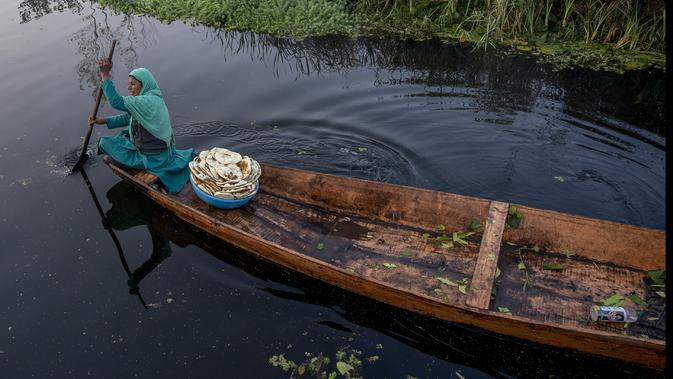 Seorang wanita Kashmir berjualan roti segar mendayung kapalnya di Danau Dal di Srinagar, Kashmir yang dikuasai India (18/10/2020). (AP Photo/Dar Yasin)