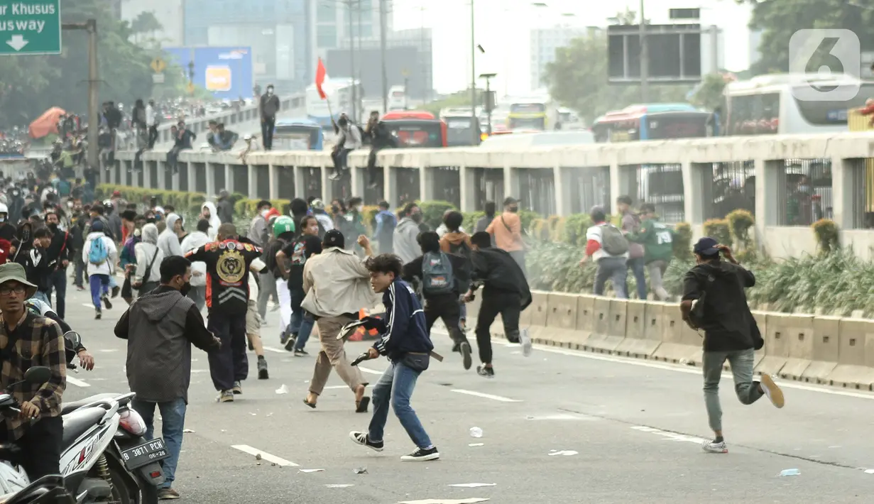 Massa aksi demo mahasiswa berlari menghindari tembakan gas air mata oleh aparat keamanan di depan Gedung DPR, Jakarta, Senin (11/4/2022). Mahasiswa yang tergabung dalam aliansi BEM SI menggelar unjuk rasa besar-besaran di depan Gedung DPR/MPR RI, Senin ini. (Liputan6.com/Angga Yuniar)