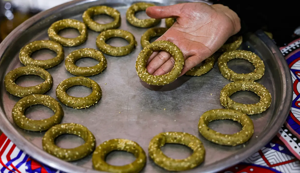 Anggota keluarga Palestina menyiapkan kue-kue tradisional untuk dijual sebagai persiapan liburan Idul Fitri mendatang, di kota Rafah, Jalur Gaza, Selasa (4/5/2021). Pembuatan kue tradisional Hari Raya Idul Fitri atau Lebaran untuk menandai akhir bulan suci Ramadhan. (KATA KHATIB/AFP)