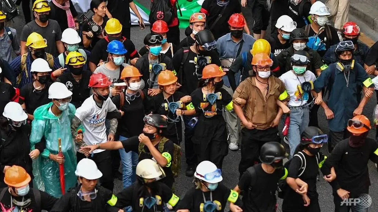 Para pengunjuk rasa bergandengan tangan saat mereka berbaris dari Monumen Kemenangan selama unjuk rasa anti-pemerintah di Bangkok pada 21 Oktober 2020.