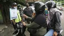 Pengendara motor memindai "barcode" melalui aplikasi PeduliLindungi sebelum memasuki Pasar Anyar di Kota Tangerang, Selasa (26/10/2021). PD Pasar Kota Tangerang memberlakukan penerapan aplikasi PeduliLindungi di dua pasar tradisional, yakni Pasar Anyar dan Pasar Poris. (Liputan6.com/Angga Yuniar)