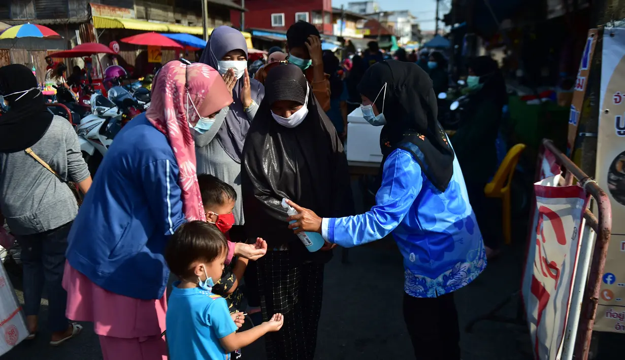 Seorang anak mengukur suhu tubuhnya sebelum memasuki pasar, sebagai bagian dari upaya untuk menghentikan penyebaran virus corona Covid-19, selama bulan suci Ramadhan di provinsi selatan Thailand, Narathiwat (17/4/2021). (AFP/Madaree Tohlala)