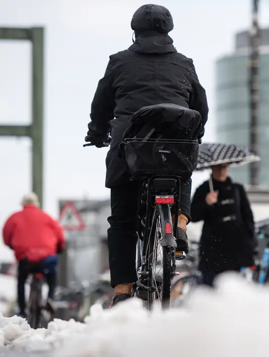 Warga memakai sepeda melalui salju di Munich, Jerman selatan, (18/4). Hujan salju yang melanda kawasan ini tidak menyurutkan warga untuk tetap beraktivitas. (AFP PHOTO / dpa / Matthias Balk / Jerman OUT)