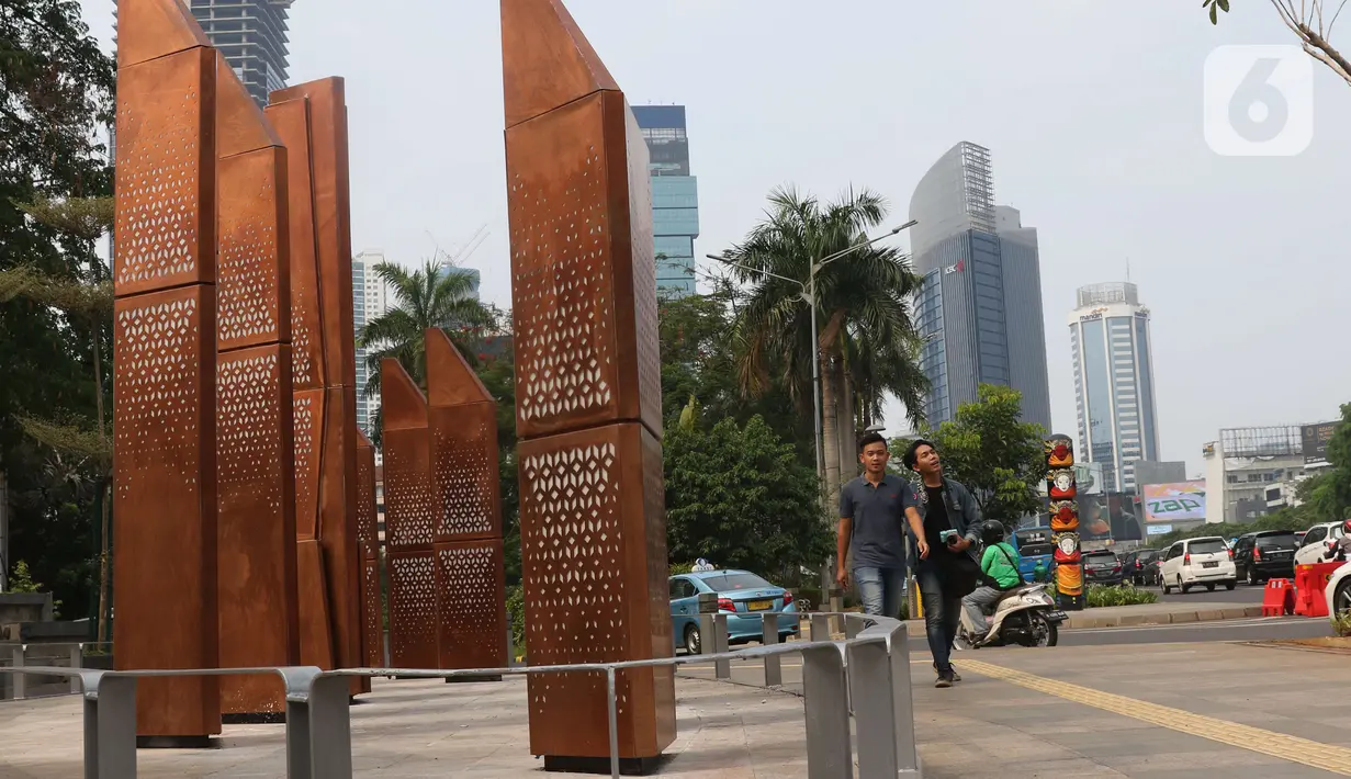Warga melintasi sebuah instalasi di kawasan Sudirman, Jakarta, Sabtu (23/11/2019). Pemprov DKI Jakarta gencar membangun dan menyediakan ruang publik bagi masyarakat, baik untuk pegawai kantoran hingga mahasiswa, yang berlalu lalang agar bebas menikmati ruang ini. (Liputan6.com/Angga Yuniar)