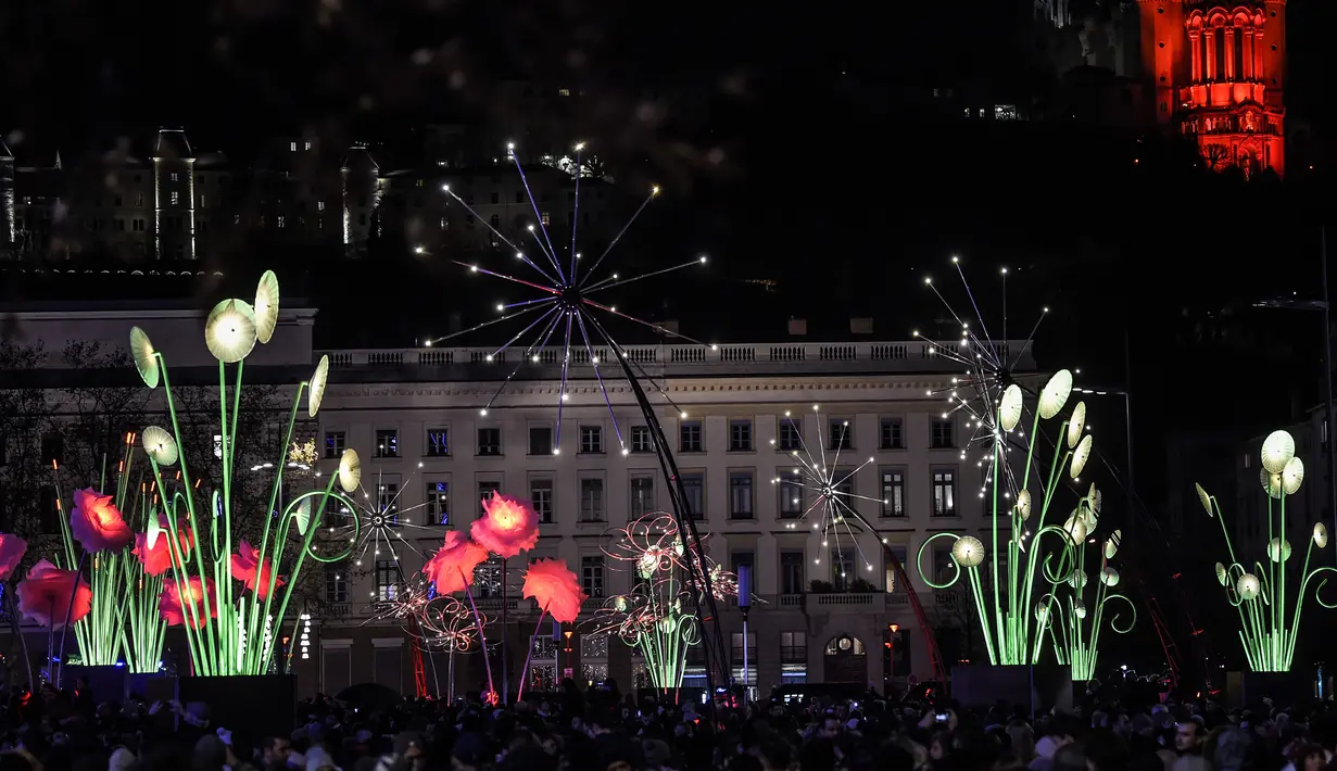 Pengunjung menghadiri festival cahaya Fete des Lumieres di Lyon, Prancis, 7 Desember 2017. Festival ini menampilkan pertunjukan cahaya di seluruh penjuru Kota Lyon, sehingga membuat kota ini dijuluki sebagai Kota Cahaya. (AFP PHOTO / PHILIPPE DESMAZES)
