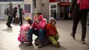 Anak-anak duduk di barang bawaannya di luar Stasiun Kereta Api Beijing, China (9/2). Sambut perayaan Imlek 2018, Jutaan warga China mulai memenuhi stasiun, bandara dan jalan yang diperkirakan akan dimulai akhir pekan ini. (AP Photo / Mark Schiefelbein)