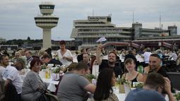 Orang-orang mengikuti acara“Berlin Freedom Dinner” di landasan pacu bekas bandara Tegel, Berlin pada 7 Agustus 2021. Acara yang dihadiri sekitar 3.000 warga tersebut untuk mengirim sinyal 'Berlin kembali!' setelah berbulan-bulan menghadapi pandemi COVID-19. (Tobias SCHWARZ/AFP)