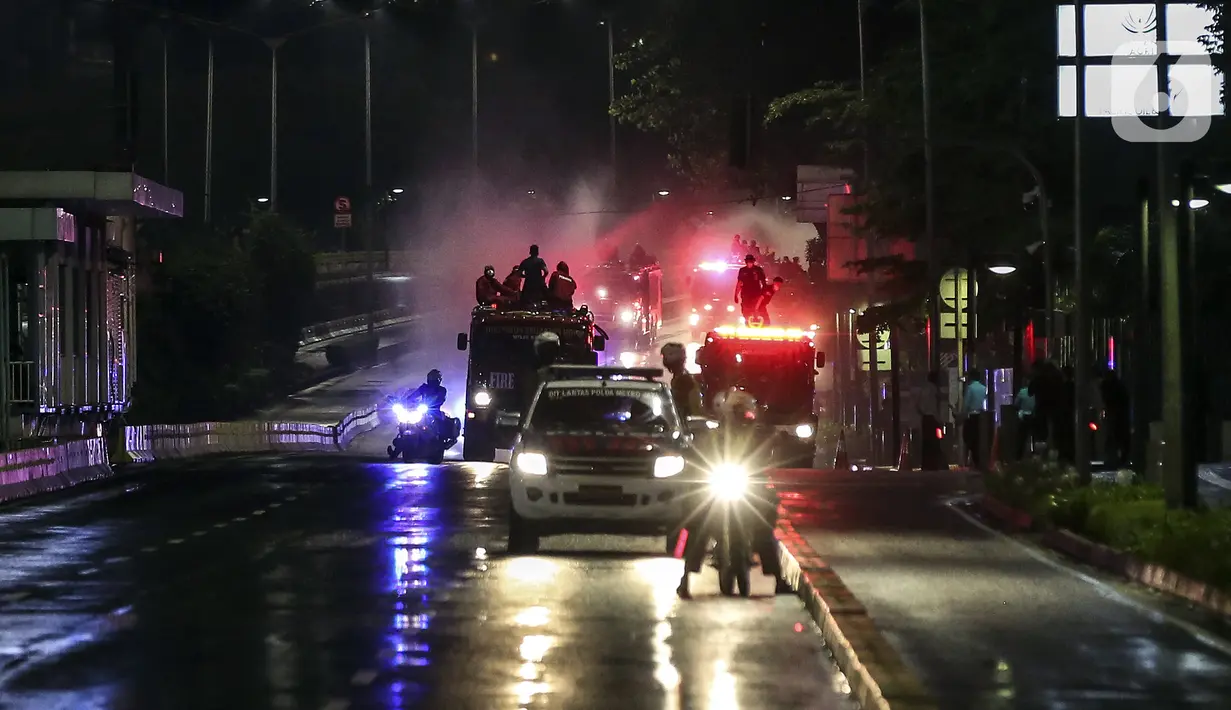Petugas dari Dinas Penanggulan Kebakaran dan Penyelamatan DKI Jakarta menyemprotkan cairan disinfektan di sekitar Jalan Jenderal Sudirman-MH Thamrin, Jakarta, Kamis (31/12/2020). Jalan Jenderal Sudirman-MH Thamrin ditutup pada malam pergantian tahun 2020 menuju 2021. (Liputan6.com/Johan Tallo)