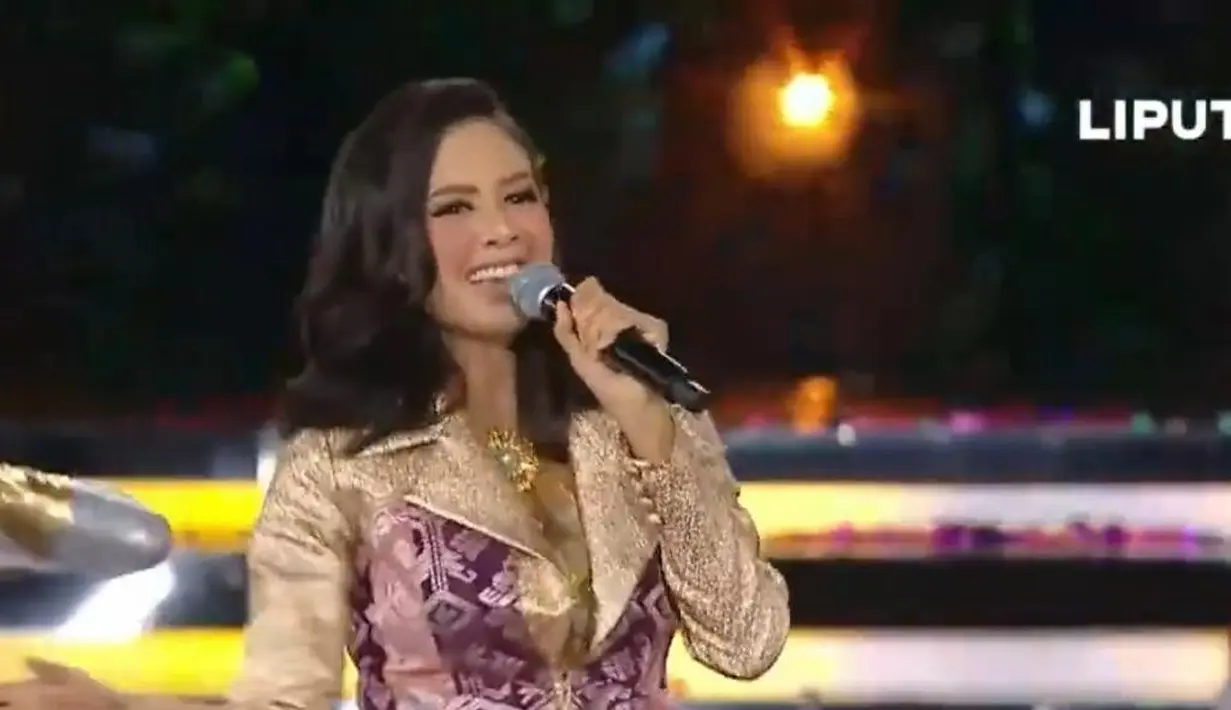 Aurelie sukses membuat para delegasi ikut bergoyang saat membawakan lagu “Cikini-Gondangdia” dan “No Comment”. Ia tampil memesona dengan set blazer motif songket bernuansa emas-ungu. [Youtube/Liputan 6]