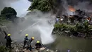 Petugas pemadam kebakaran mengambil air dari sungai untuk memadamkan api yang membakar kawasan kumuh di Manila, Filipina (11/8). (AFP Photo/Noel Celis)