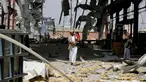 Seorang pria menggendong anaknya di sebuah bangunan pabrik pipa dan pompa air yang hancur akibat serangan udara Arab Saudi di Sanaa, Yaman, Kamis (15/9). Dalam serangan ini tidak ada korban jiwa. (REUTERS/Khaled Abdullah)