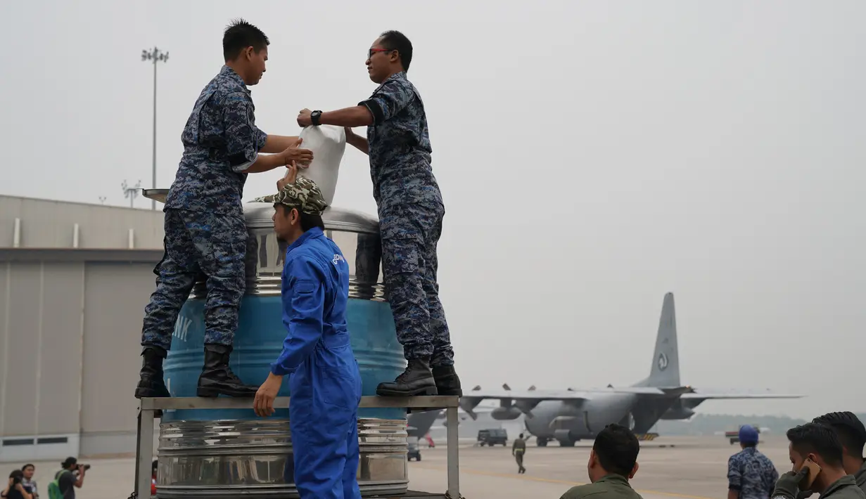 Tim penyemaian awan bersama prajurit Angkatan Udara menyiapkan tangki berisi larutan air garam di Pangkalan Udara Militer Subang, Malaysia, Kamis (19/9/2019). Malaysia melakukan operasi penyemaian awan untuk mendorong hujan dalam mengatasi kabut asap yang melanda. (AP Photo/Vincent Thian)