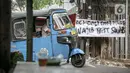Sebuah bajaj melintas di dekat spanduk peringatan untuk pemudik di kawasan Kartini, Sawah Besar, Jakarta, Senin (17/5/2021). Spanduk tersebut untuk memperingati warga yang kembali dari mudik lebaran agar membawa surat bebas COVID-19. (Liputan6.com/Faizal Fanani)