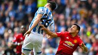 Pemain Huddersfield Town, Christopher Schindler berebut bola dengan penyerang sayap Manchester United, Alexis Sanchez pada pekan ke-37 Liga Inggris di John Smith's Stadium, Minggu (5/5/2019). MU gagal ke Liga Champions musim depan setelah ditahan Huddersfield Town 1-1. (Anthony Devlin/PA via AP)